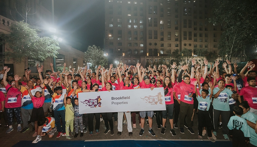 Large group of enthusiastic participants posing with a Brookfield Properties banner before a night run event at Downtown Powai