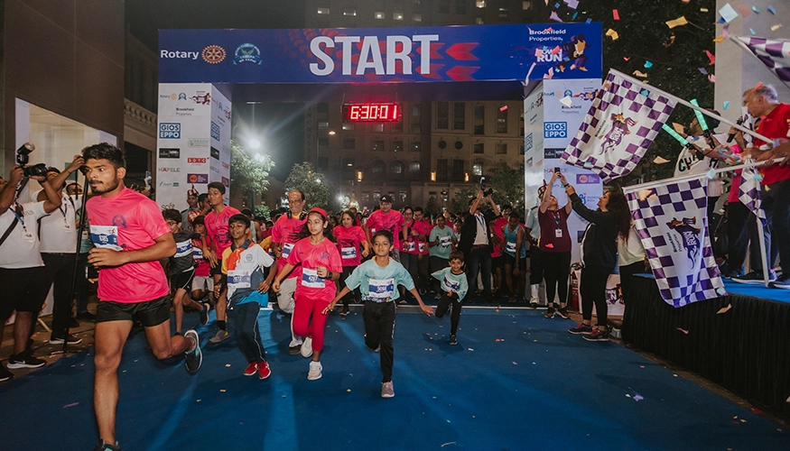 Participants of all ages starting a night run event at Downtown Powai, running under a ‘START’ banner with cheering spectators