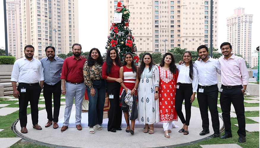 Group of people standing in front of a decorated Christmas tree at Downtown Powai, smiling and posing for the camera